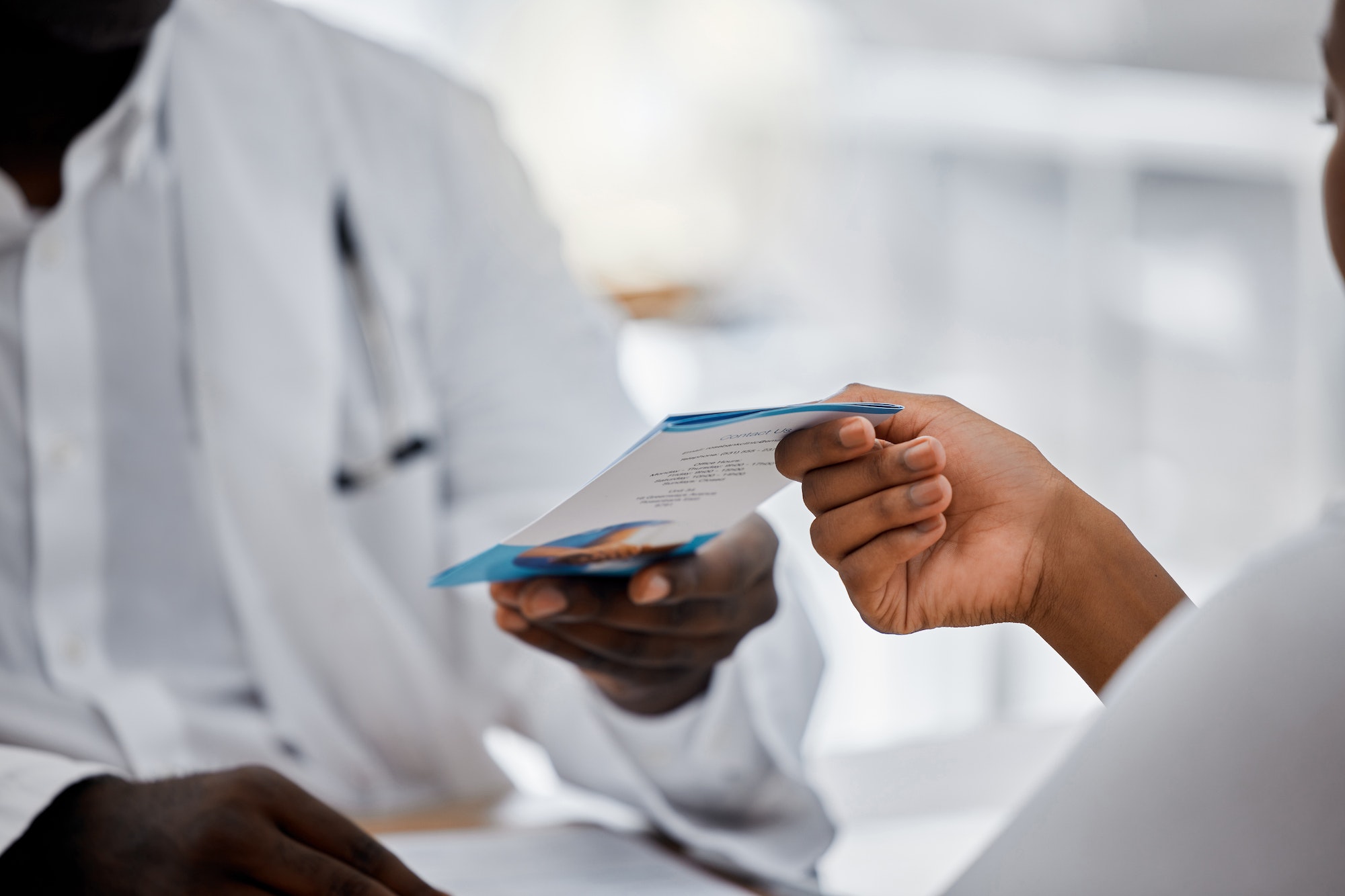 Hands of doctor giving flyer to patient about hospital help, medical clinic contact us information